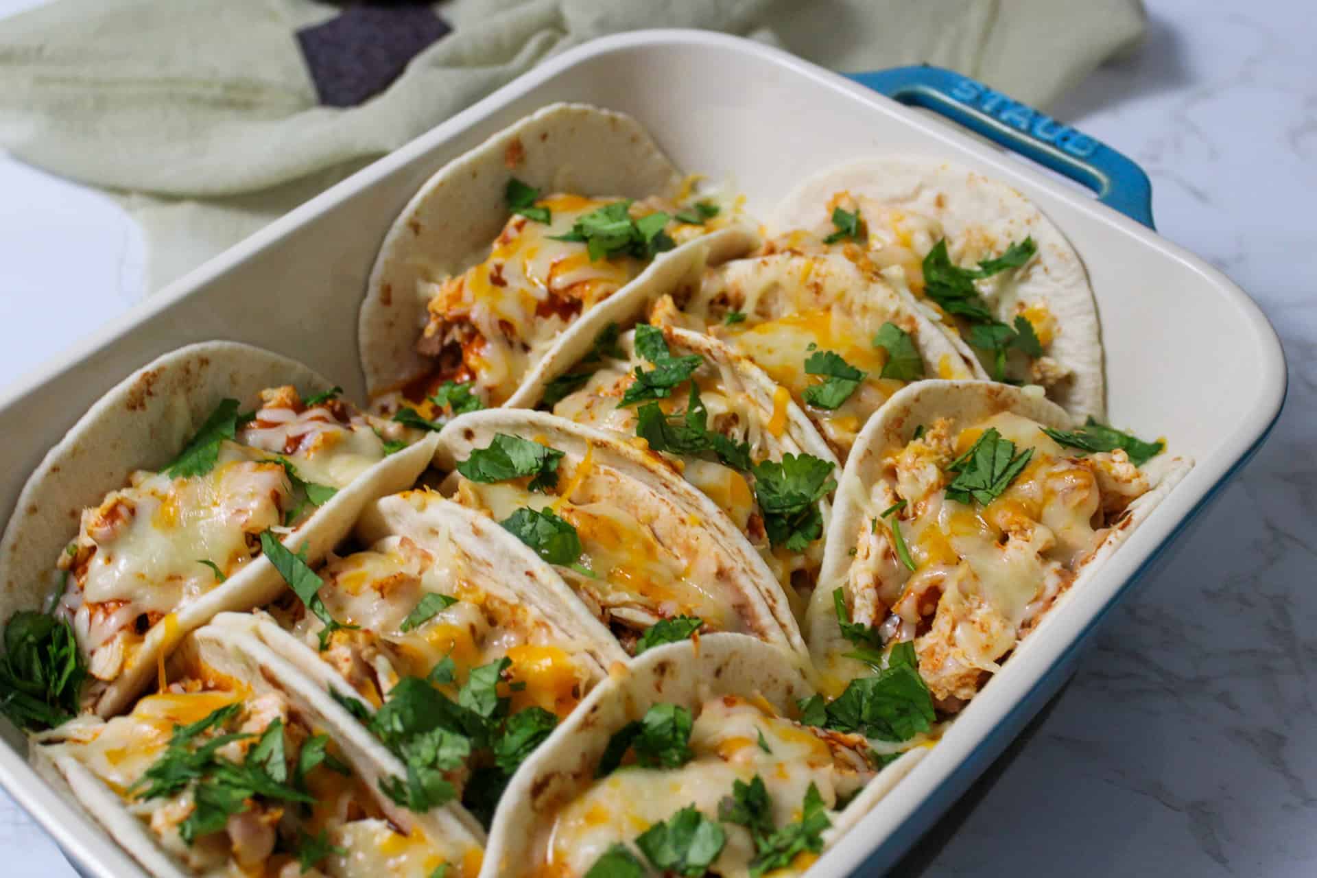A baking dish full of cheesy oven baked chicken tacos