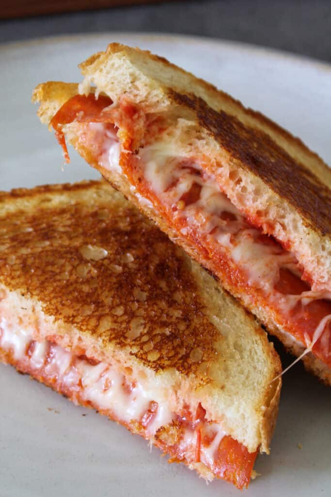 Two halves of a pepperoni pizza panini stacked on a plate