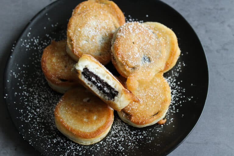A plate of deep fried oreos, one with a bite taken out of it