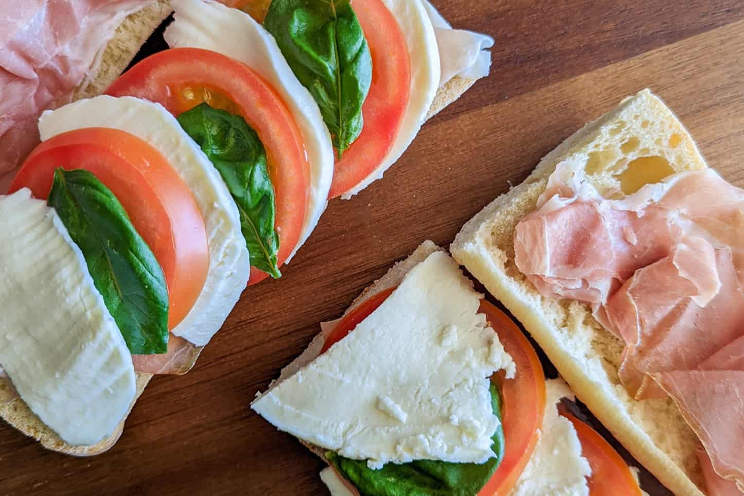 A close up of a caprese sandwich with prosciutto