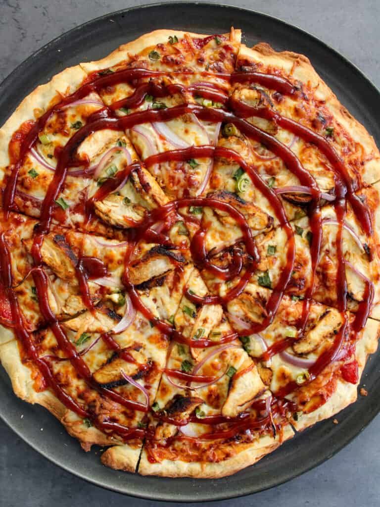 A thin crust BBQ chicken pizza topped with barbecue sauce