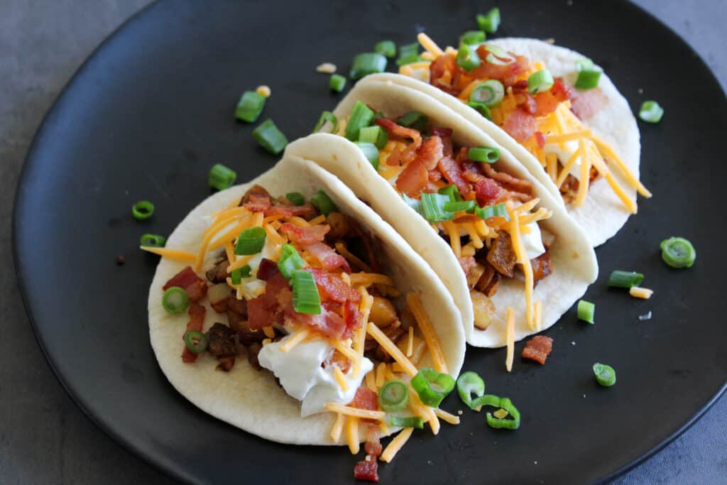Three loaded baked potato tacos served on a plate