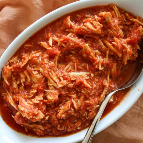 A dish of gluten free shredded slow cooker chicken parmesan