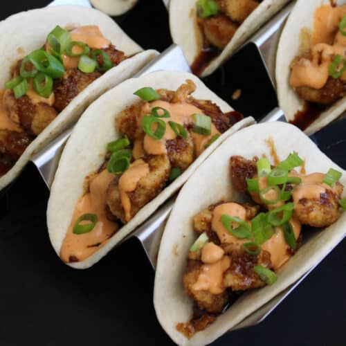 Asian crispy chicken tacos in flour tortillas, garnished with scallions