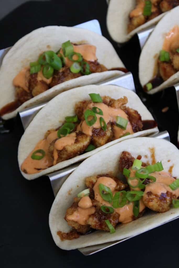 Three Asian fried chicken tacos with sesame glaze and sriracha aioli