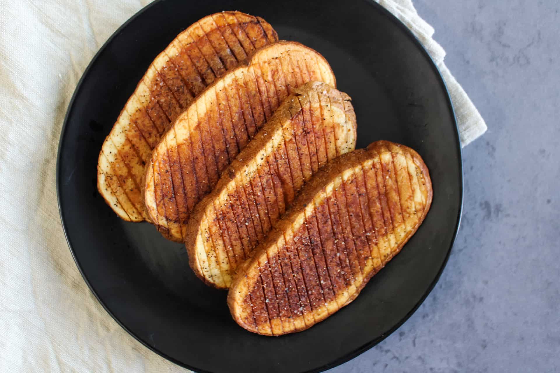 A plate of fried accordion potatoes seasoned with salt and pepper