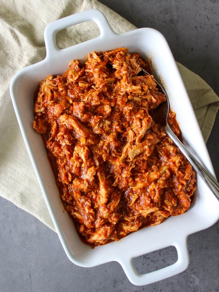 A serving dish of shredded crockpot chipotle chicken