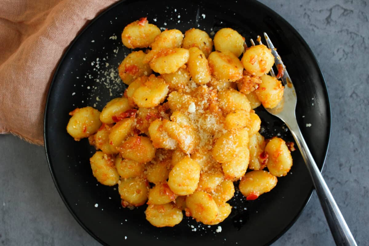 Spicy calabrian chili gnocchi on a plate topped with grated parmesan cheese
