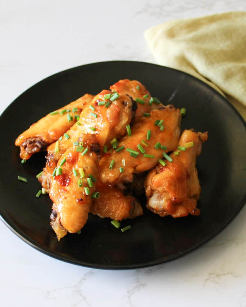 A plate of agave chili lime chicken wings garnished with chives