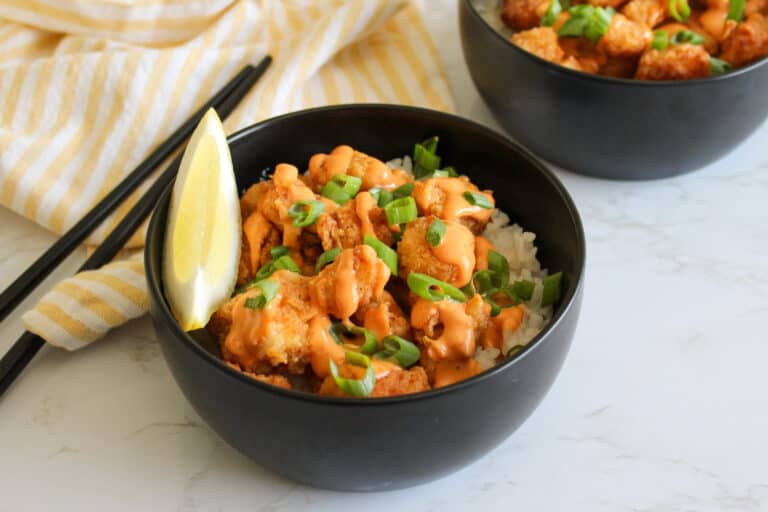 Fried white fish and rice bowl topped with sriracha aioli and scallions