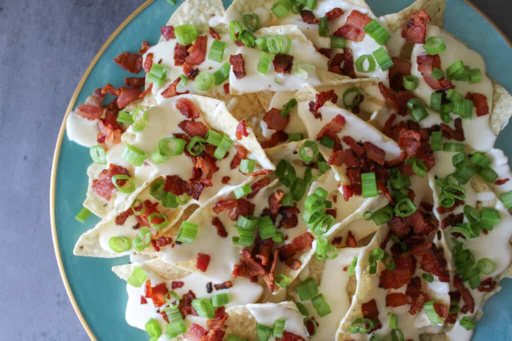 Nachos topped with beer cheese sauce, bacon bits, and scallions.