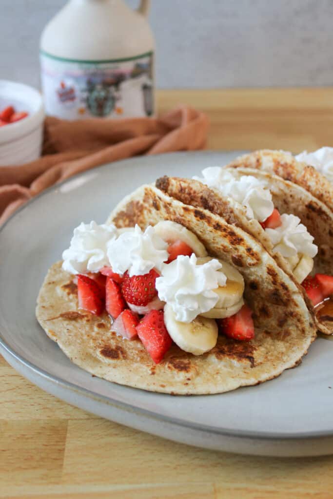 French toast style breakfast tacos with strawberries, bananas, and whipped cream.