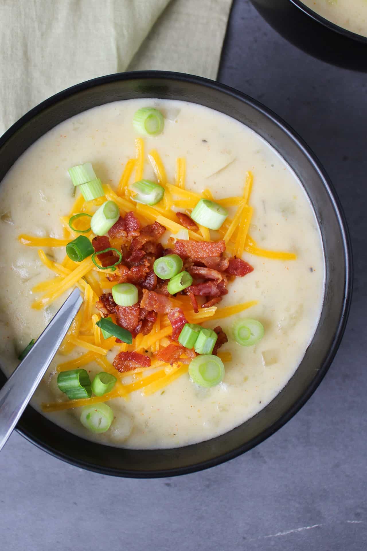 A bowl of loaded potato soup with bacon, cheddar, and scallions as toppings.