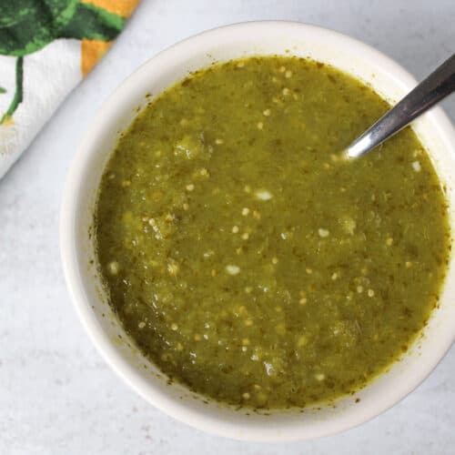 A small dish of Mexican verde sauce with a spoon.