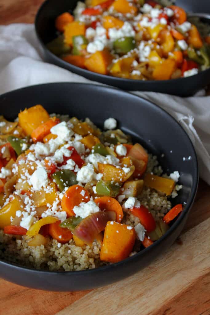 Two harvest bowls with quinoa and vegetables and feta cheese.
