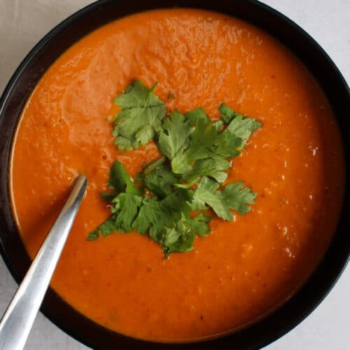 A bowl of spicy Indian tomato soup garnished with cilantro.