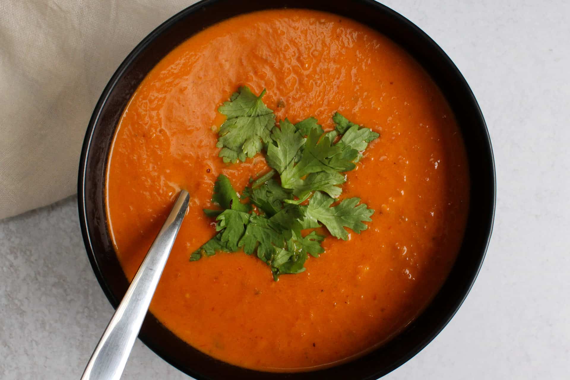 A bowl of spicy Indian tomato soup garnished with cilantro.
