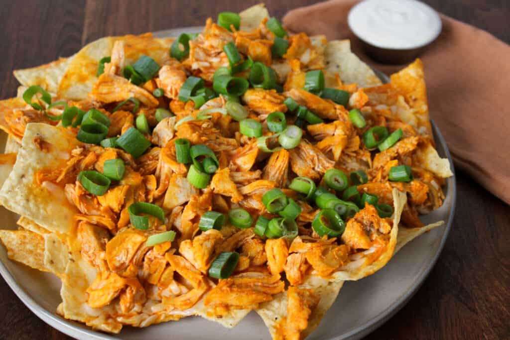 Buffalo chicken nachos topped with scallions.
