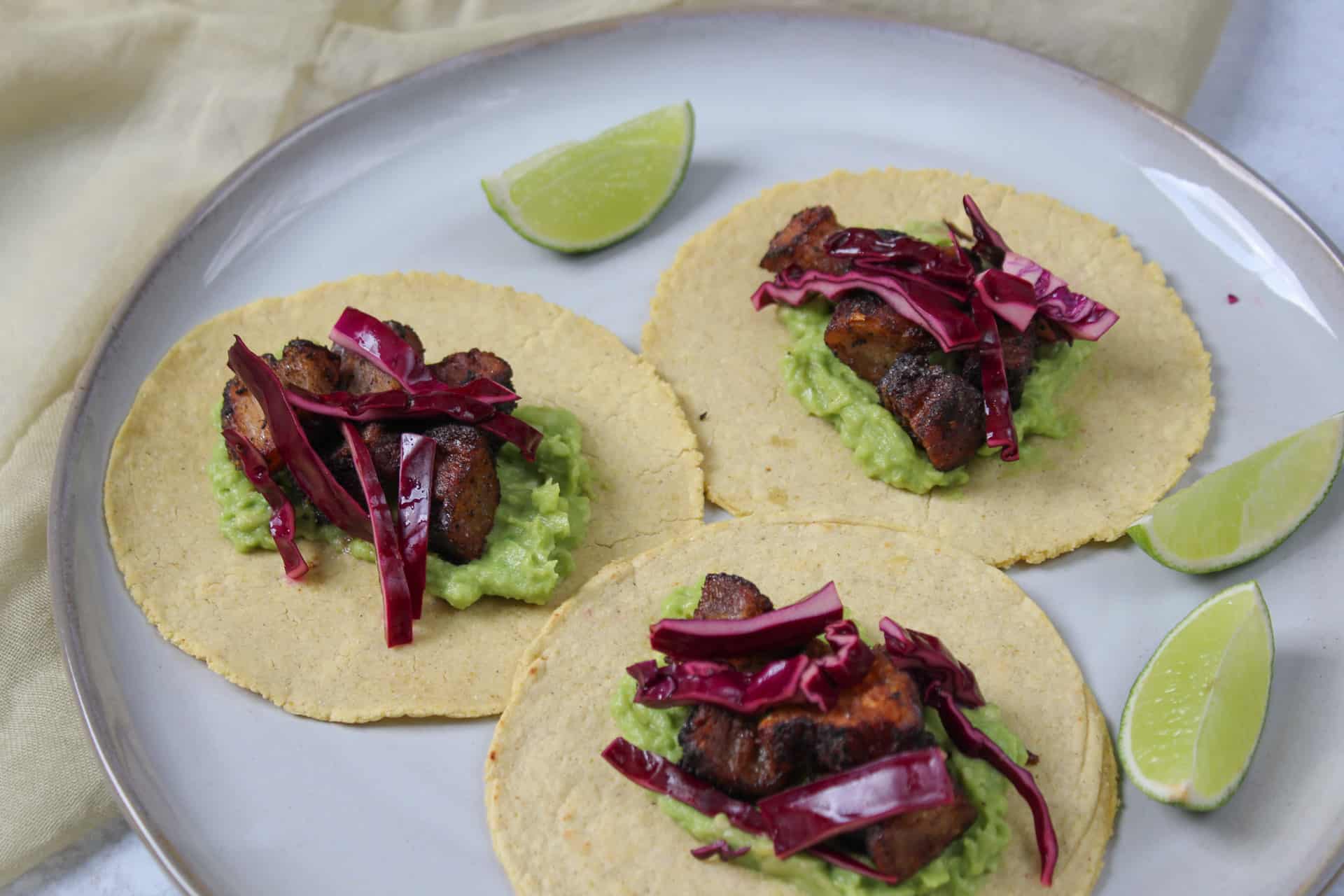 A plate of three pork belly tacos.