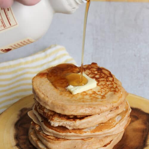 Pouring maple syrup over buttermilk protein pancakes.
