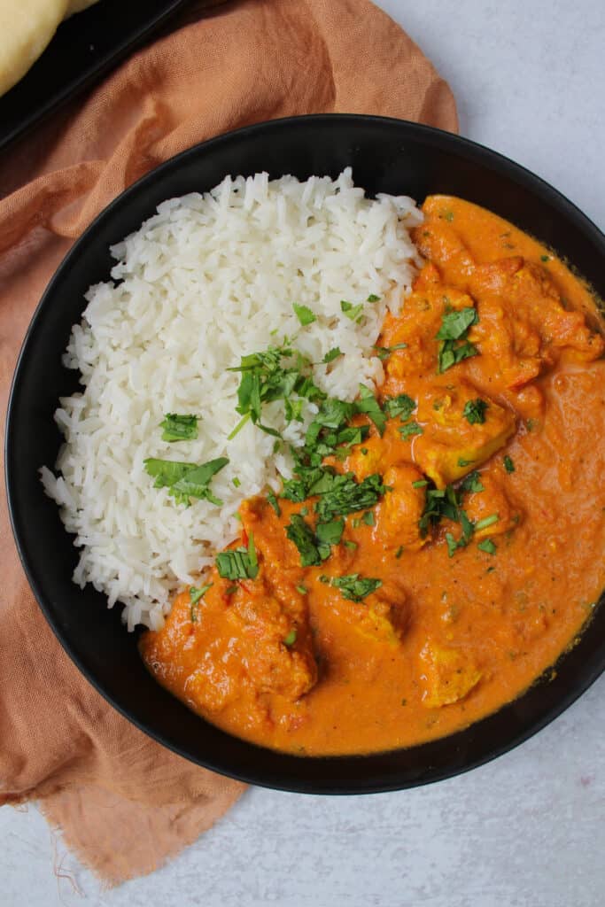 A bowl of spicy butter chicken and rice.