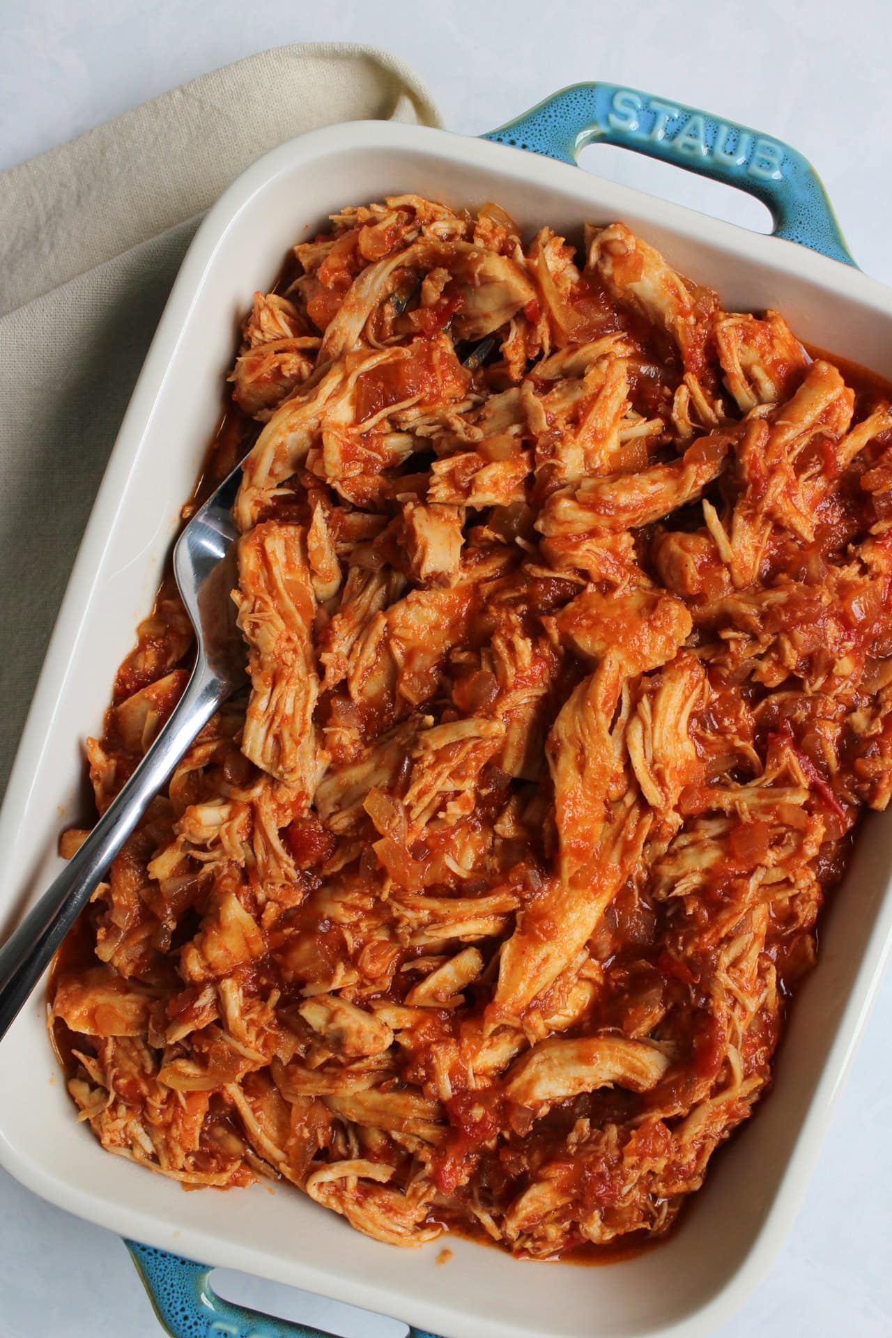 Saucy shredded Korean gochujang chicken in a serving tray.