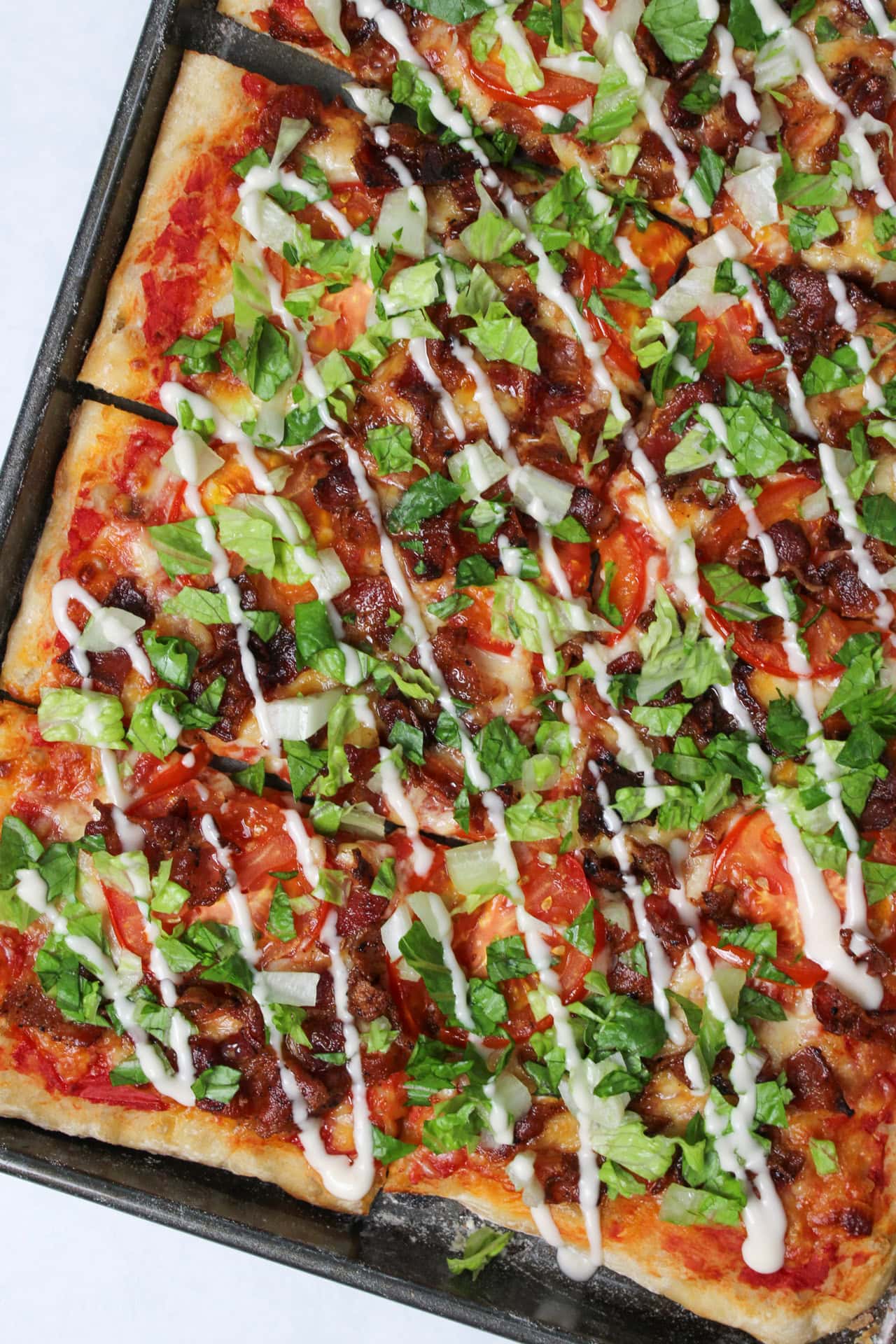 A sheet pan BLT pizza with garlic aioli drizzle.