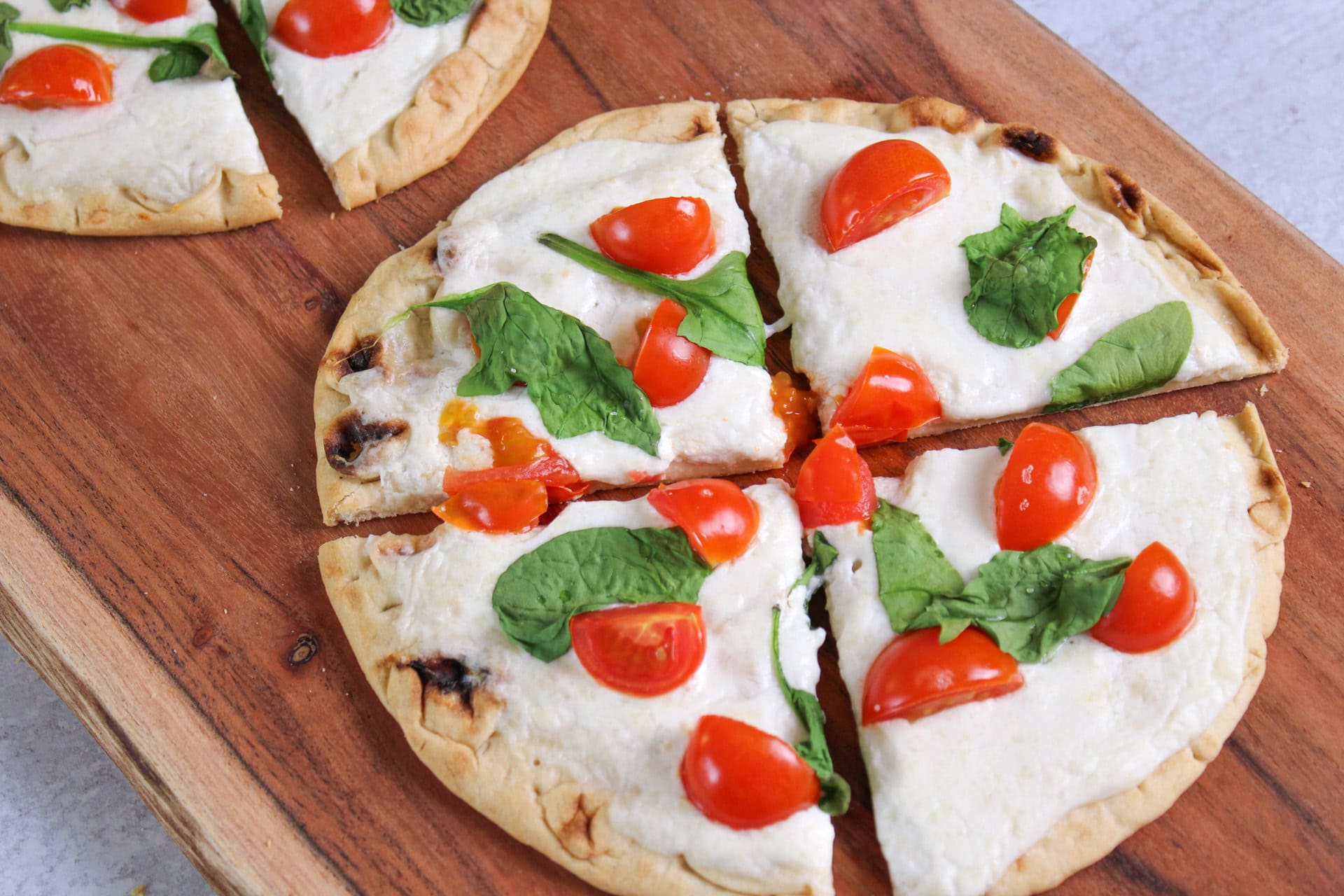 Cottage cheese flatbread pizza with cherry tomatoes and spinach.