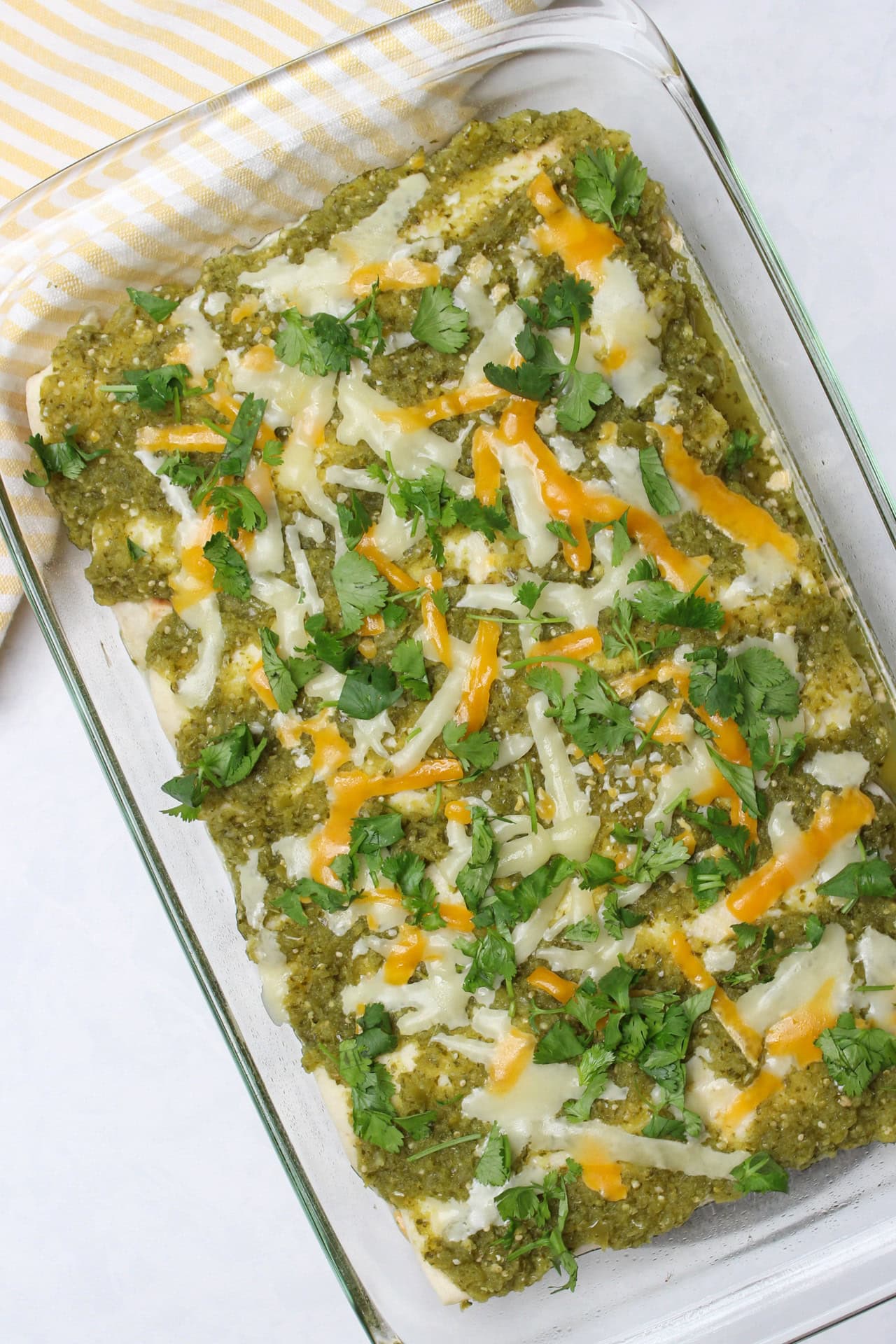 A tray of chicken enchiladas with verde sauce.