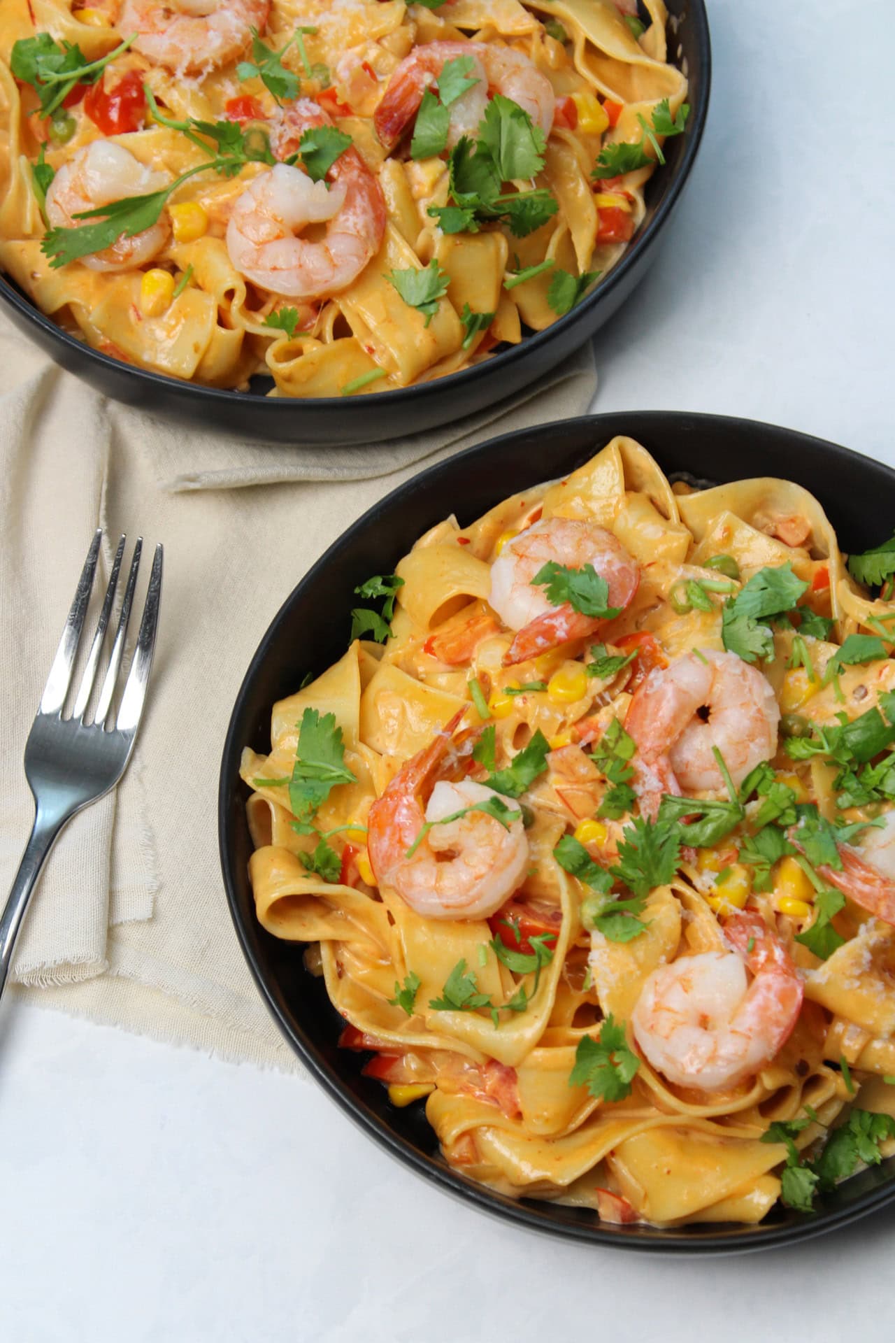Two bowls of spicy seafood pasta featuring a pan-fried shrimp, pappardelle, a southwest veggie medley, and a chipotle cream sauce. 
