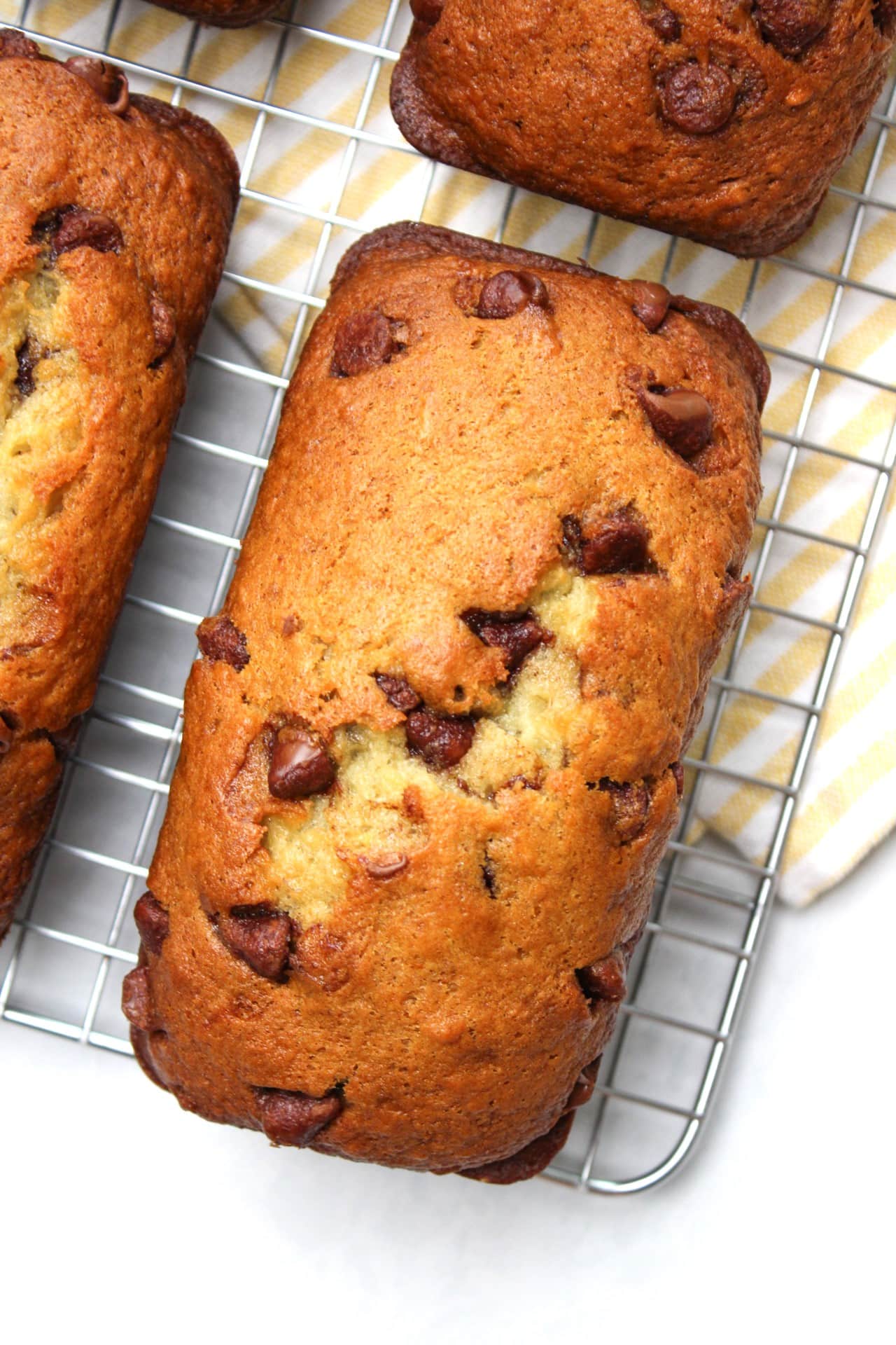 A freshly baked mini loaf of chocolate chip banana bread on a wire rack.