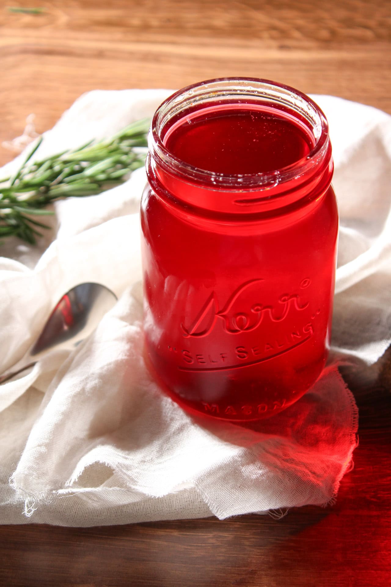 A bright red, rosemary cranberry simple syrup in a mason jar.