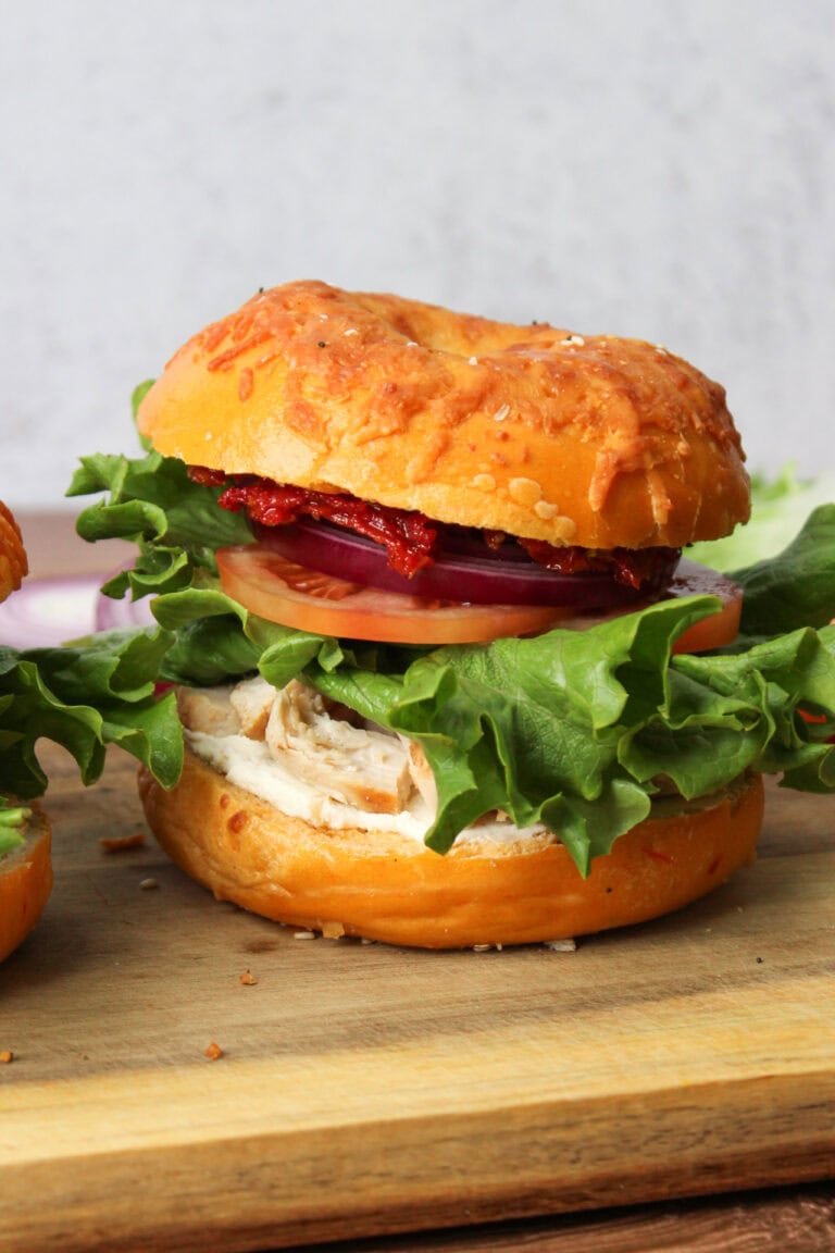 A bagel sandwich with chicken, cream cheese, and sun dried tomatoes.