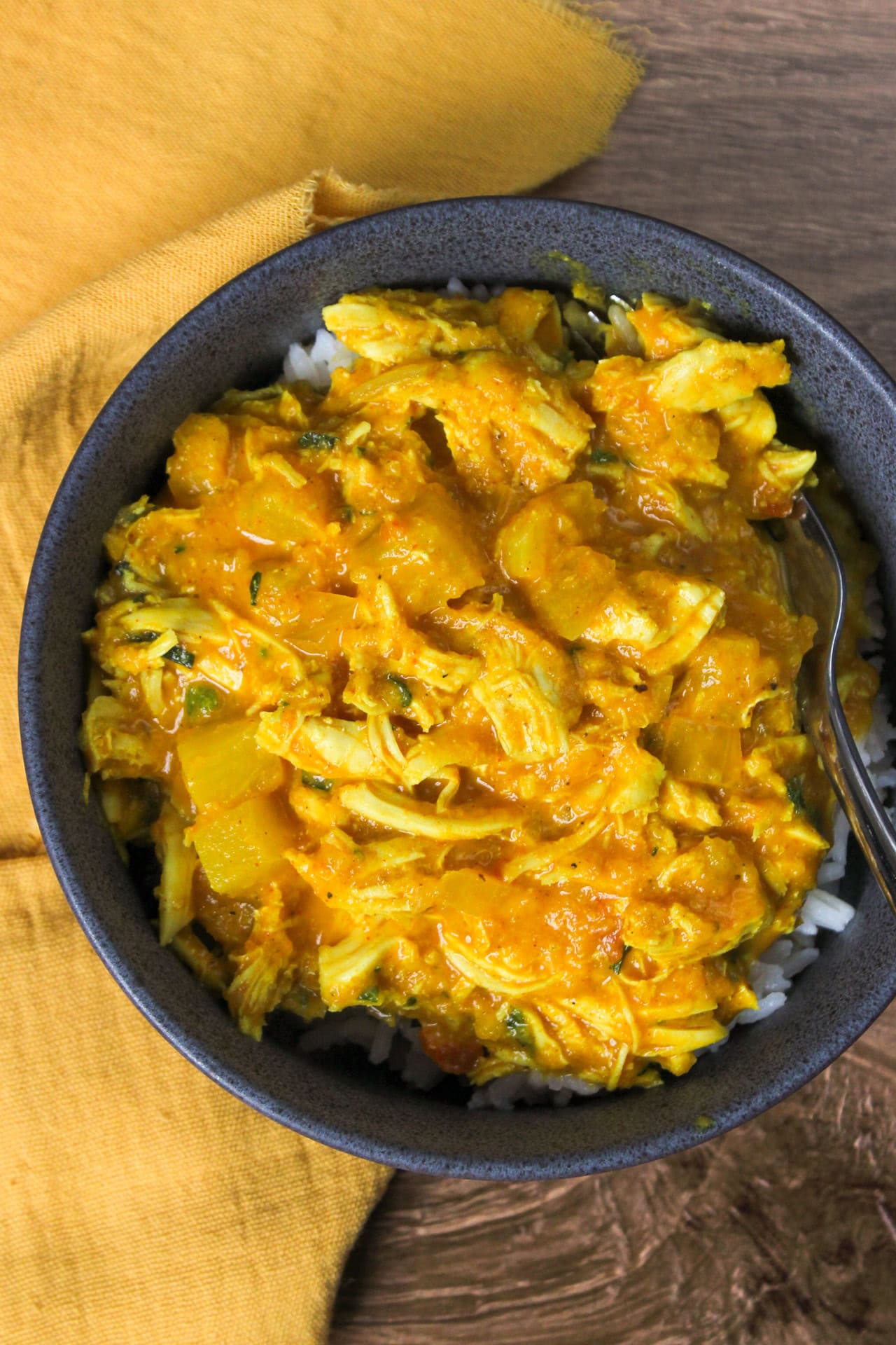 Indian chicken pineapple curry with coconut milk and rice served in a stoneware bowl.