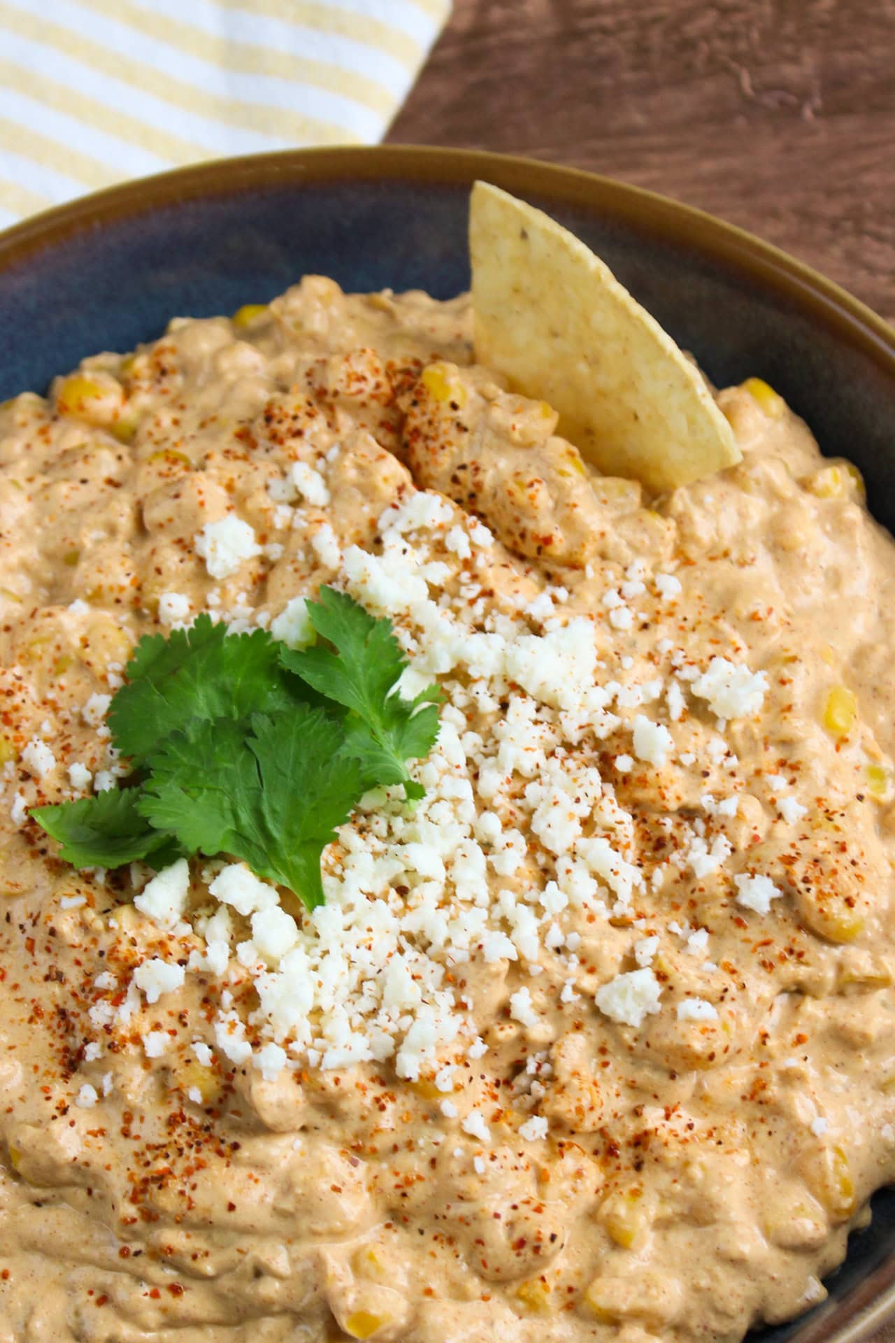 A bowl of Mexican street corn dip topped with crumbled cotija cheese and fresh cilantro.