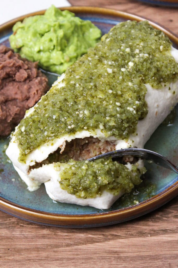 A carnitas burrito being cut open.