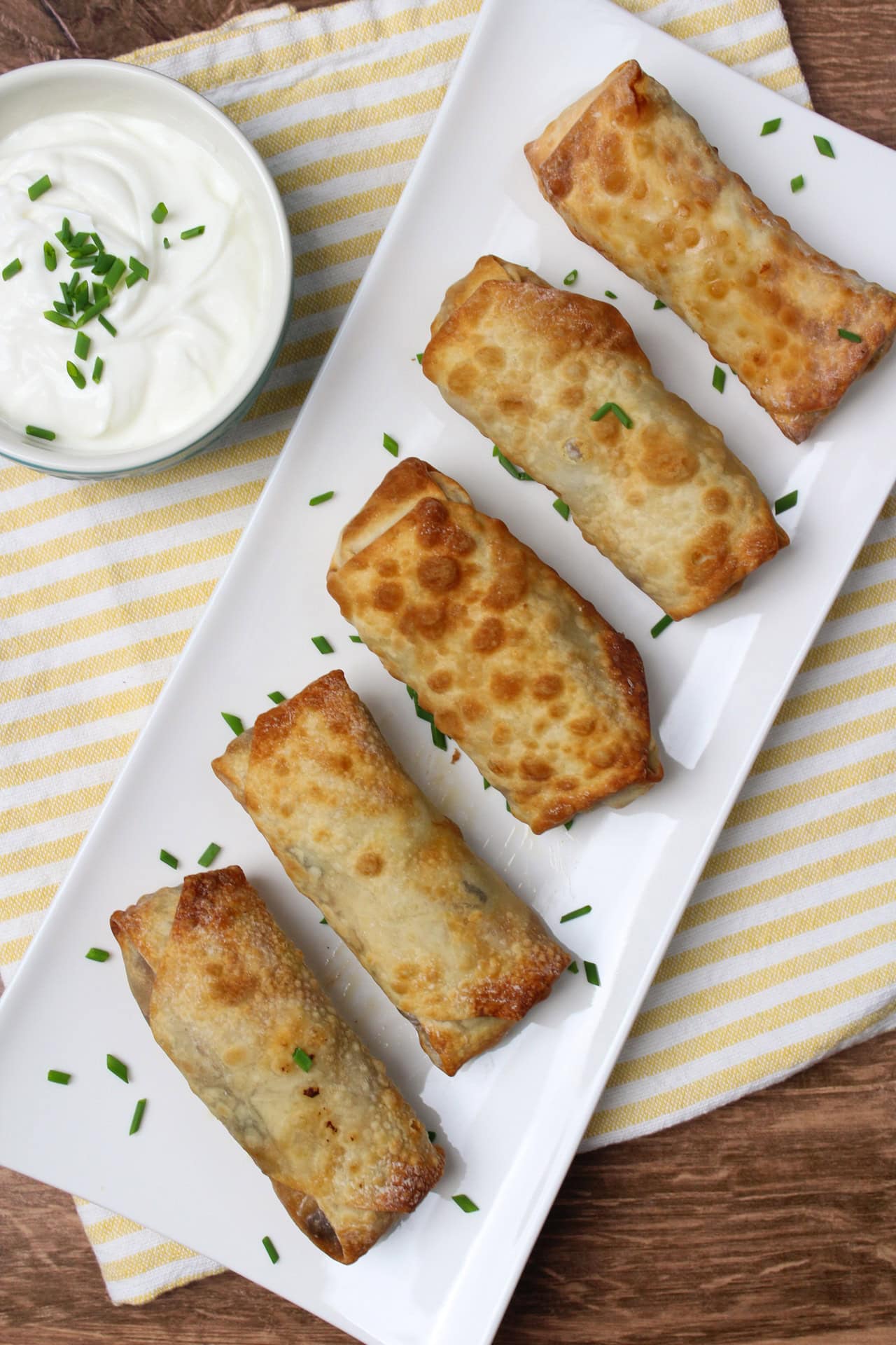 5 southwest egg rolls in a row on a white plate. 