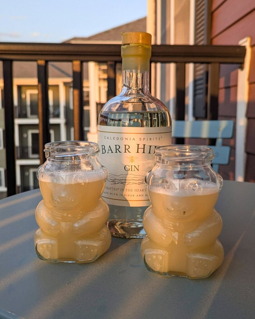 Two bee's knees cocktails in bear shaped glasses.