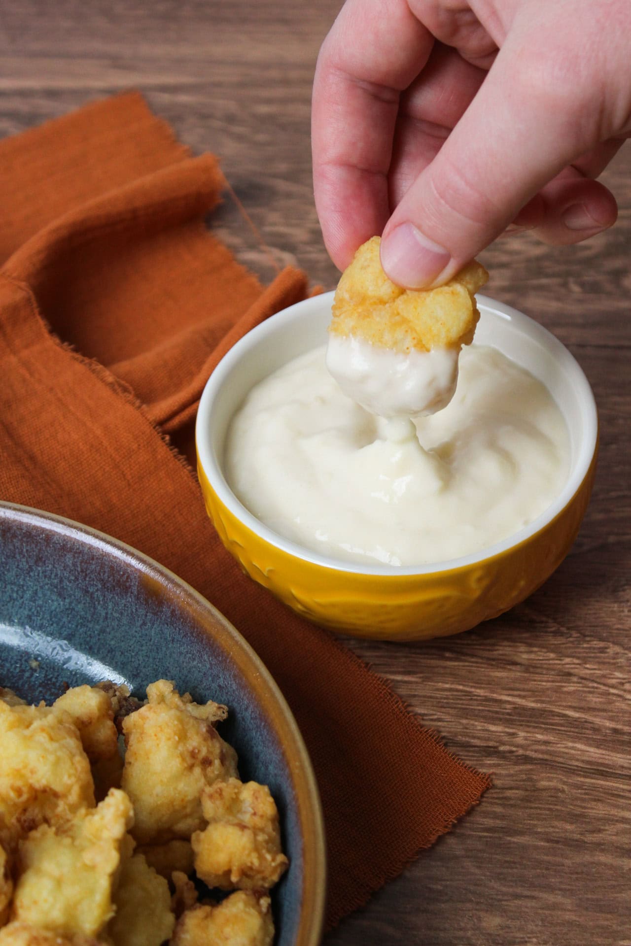 Fried cauliflower being dipped into roasted garlic aioli.