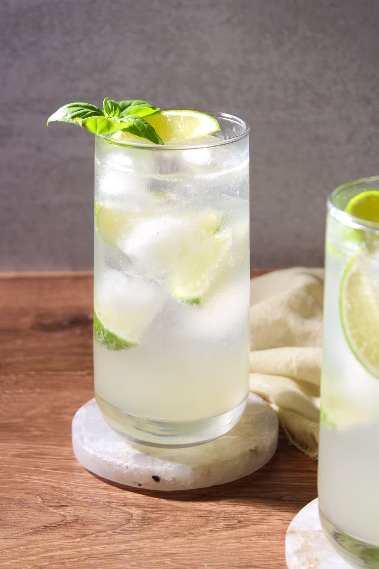 A gin basil mojito garnished with lime and fresh basil in a collins glass.