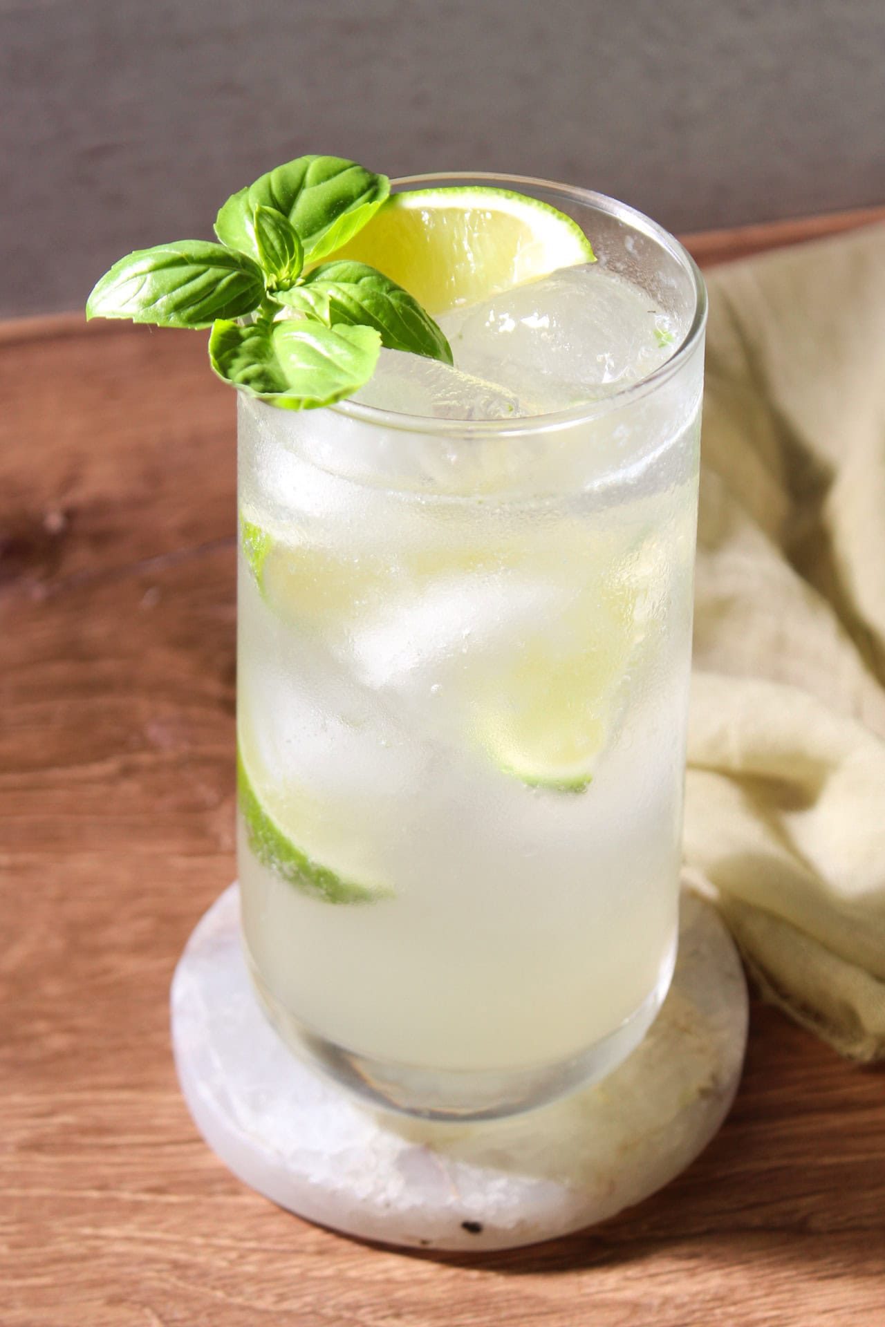 Gin basil mojito garnished with lime wedges and a sprig of bail in a collins glass. 