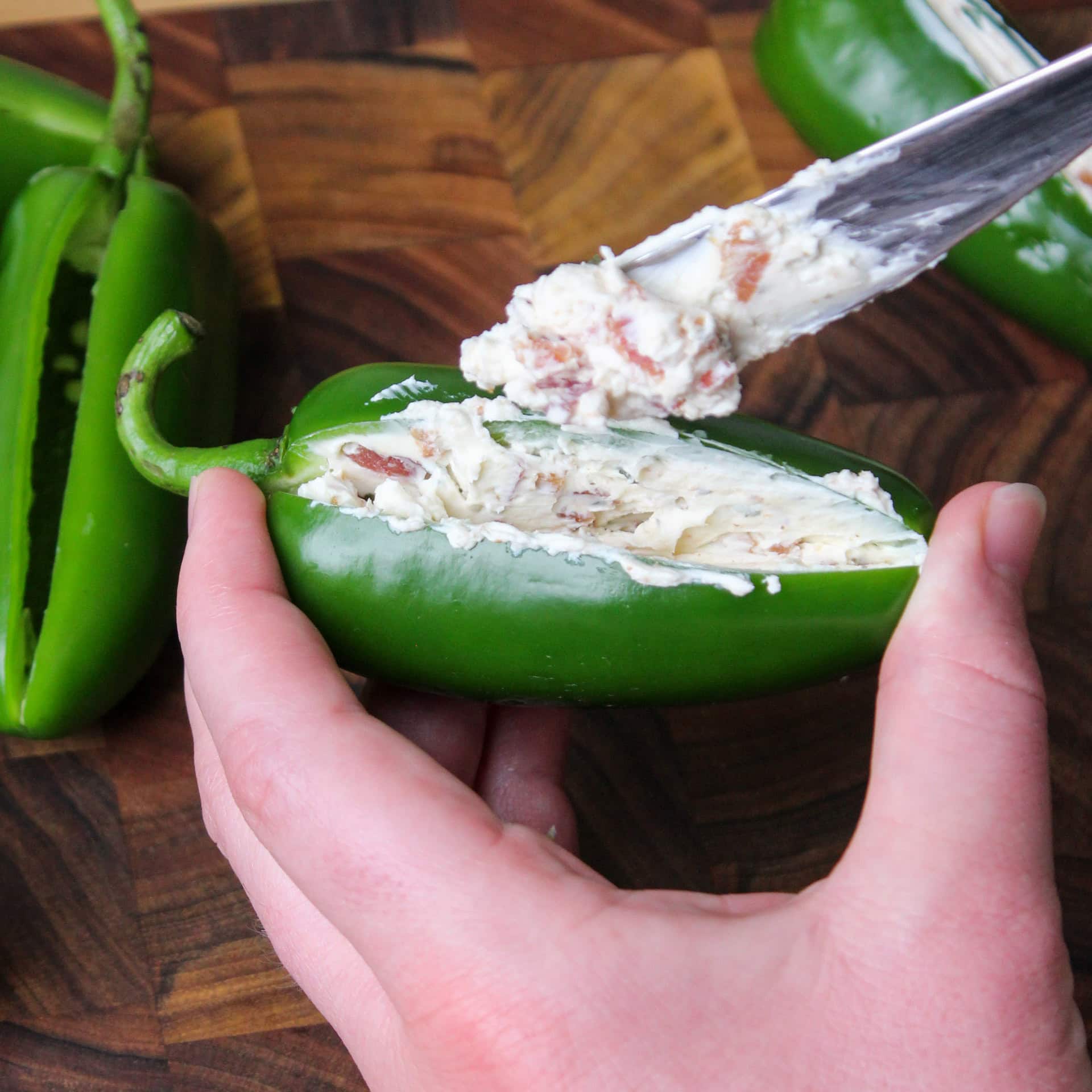 Stuffing a jalapeno popper with bacon cream cheese.