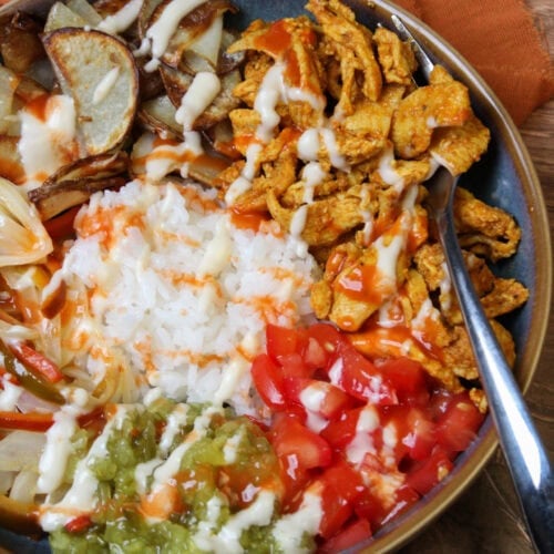 A chicken shawarma bowl with rice, tomatoes, pickle relish, potatoes, and garlic aioli.