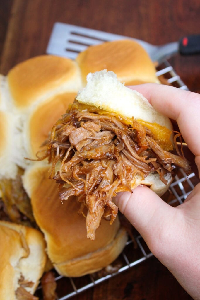 A pulled pork slider with cheddar cheese on a Hawaiian roll.