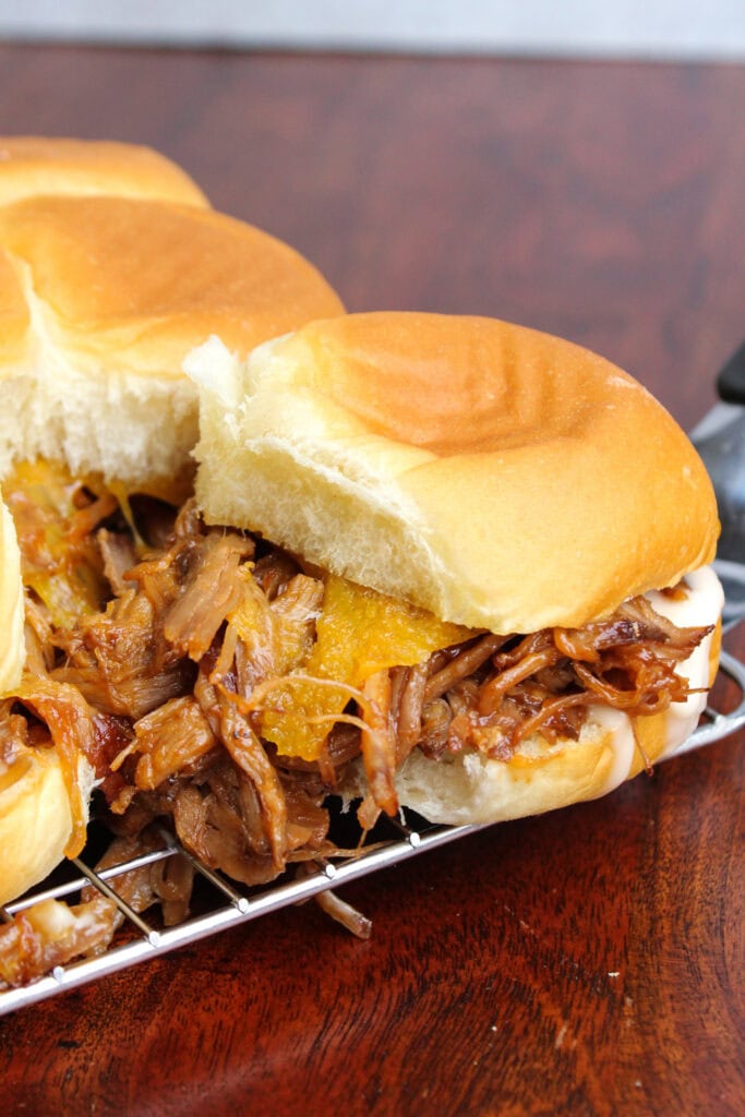 Pulled pork slider on a Hawaiian roll with cheddar cheese.