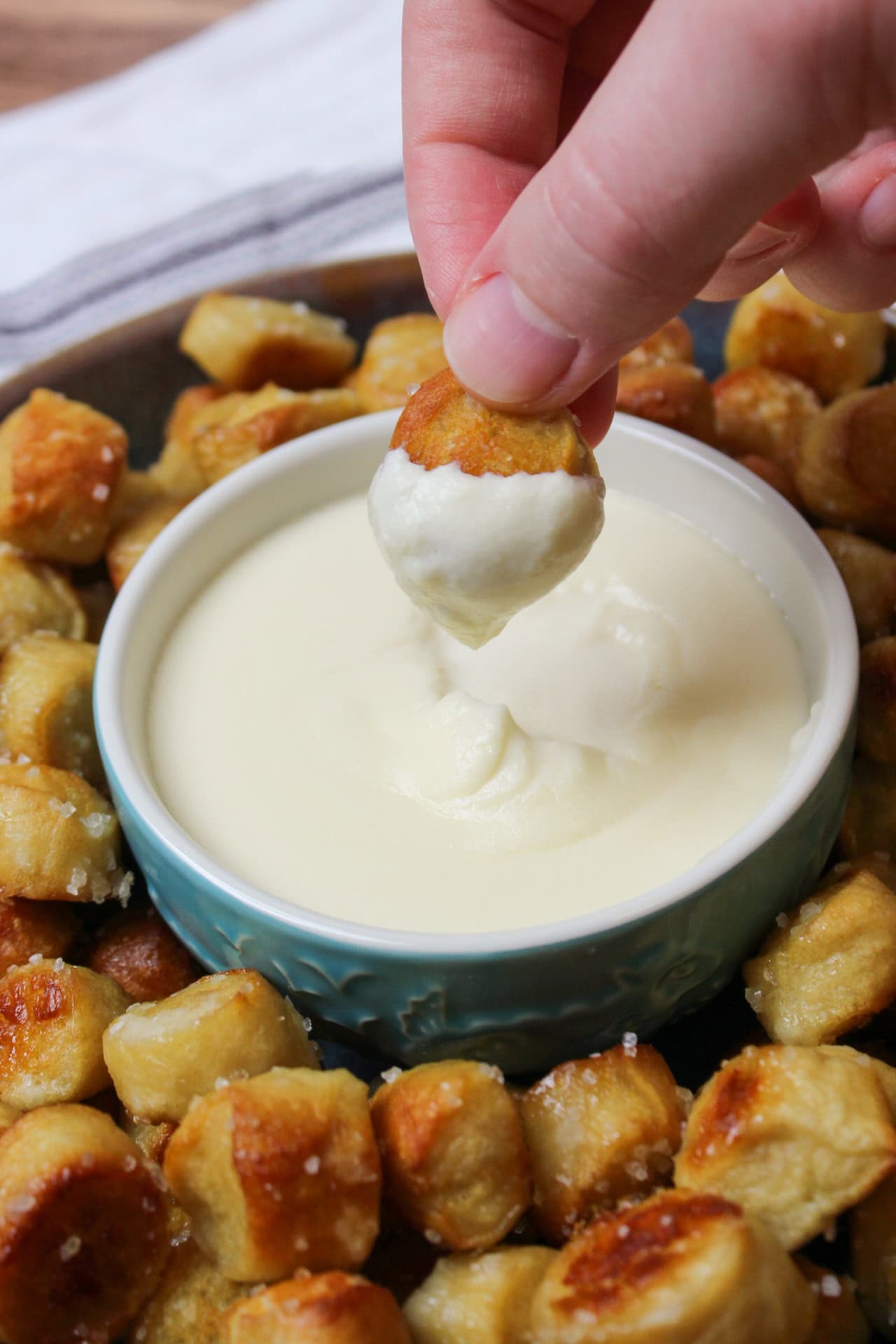 Dipping a golden brown soft pretzel bite into beer cheese sauce.