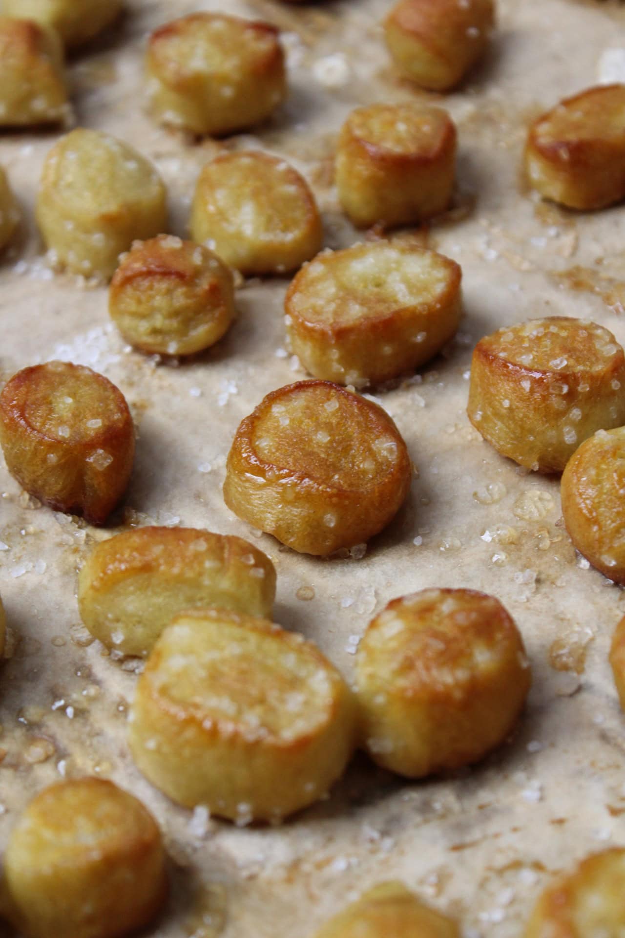 Golden brown salted soft pretzel bites made from pizza dough on a baking sheet.