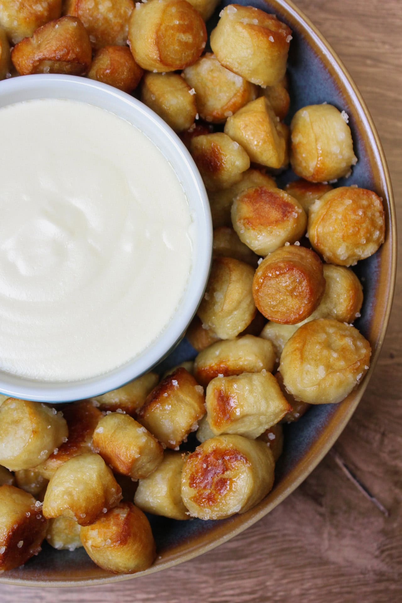 A blue bowl of salted pretzel bites served with beer cheese dip.