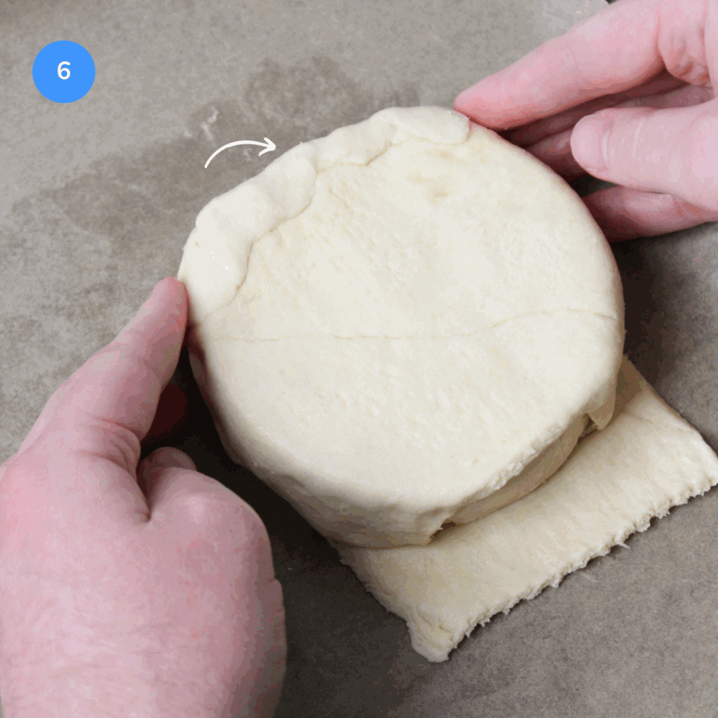 Folding pastry dough over baked brie en croute.