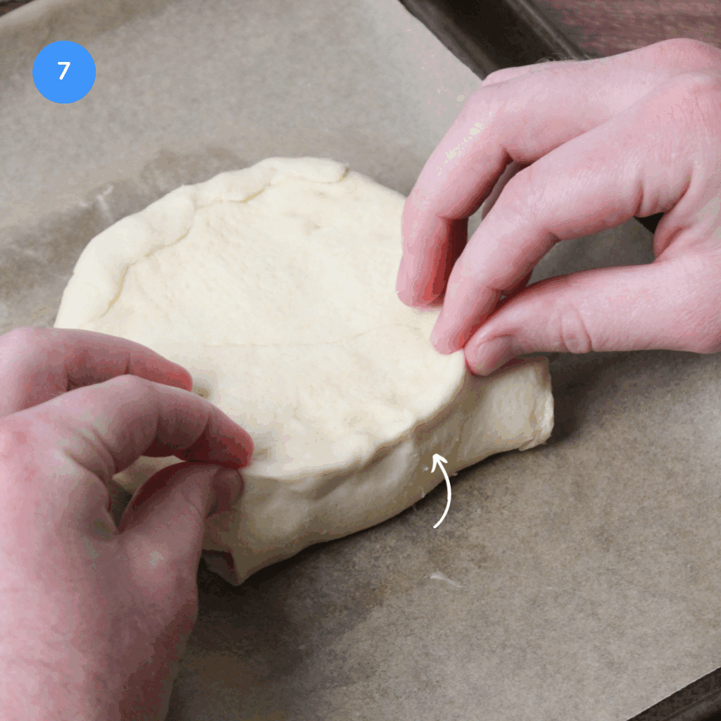 Folding pastry dough to encase brie before baking.